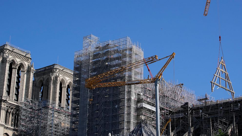 Vigas de carvalho foram erguidas no telhado da catedral de Notre Dame, devastada pelo fogo, enquanto a multidão assistia ao longo do Sena.