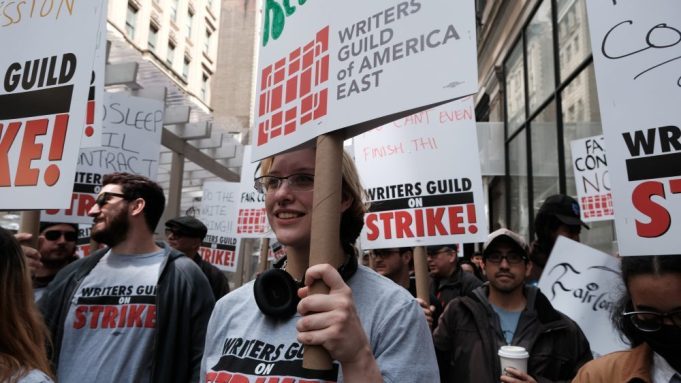 CIDADE DE NOVA IORQUE - 03 DE MAIO: Membros do Writers Guild of America (WGA) East seguram cartazes enquanto caminham pelo segundo dia em um piquete fora do escritório da Netflix em Nova York em 3 de maio de 2023 na cidade de Nova York.  Os membros do WGA abandonaram o primeiro dia de uma greve eleitoral em Hollywood depois que o conselho de administração do Writers Guild of America, que inclui os capítulos da Costa Oeste e da Costa Leste, votou unanimemente pela convocação de uma greve.  As negociações entre um importante sindicato e a associação comercial que representa os principais estúdios de Hollywood não conseguiram evitar a primeira greve em mais de 15 anos.  Os sindicalistas declararam que não estão a ser pagos de forma justa na era do streaming e procuram aumentos salariais e mudanças estruturais no modelo de negócio.  (Foto de Spencer Platt/Getty Images)