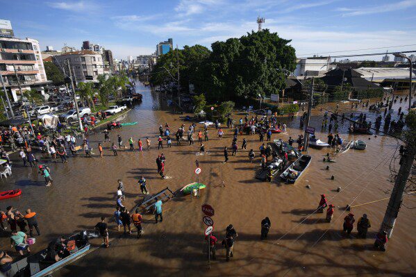 Voluntários se reúnem para ajudar moradores a evacuar área inundada por chuvas torrenciais, em Porto Alegre, Brasil, terça-feira, 7 de maio de 2024. (AP Photo/Andre Penner)