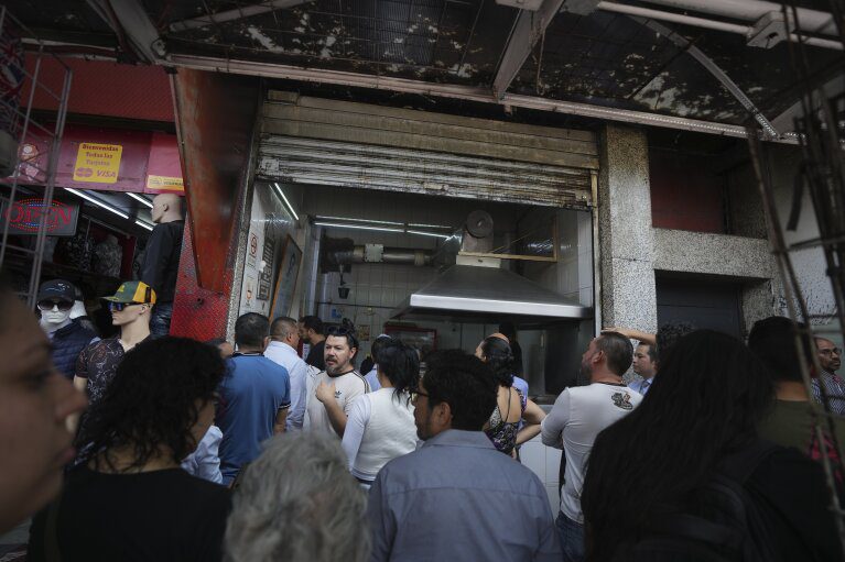 Clientes fazem fila para pedir tacos no estande do Tacos El Califa de León, na Cidade do México, quarta-feira, 15 de maio de 2024. Tacos El Califa de León é o primeiro estande de tacos a receber uma estrela Michelin do guia gastronômico francês.  (Foto AP/Fernando Llano)