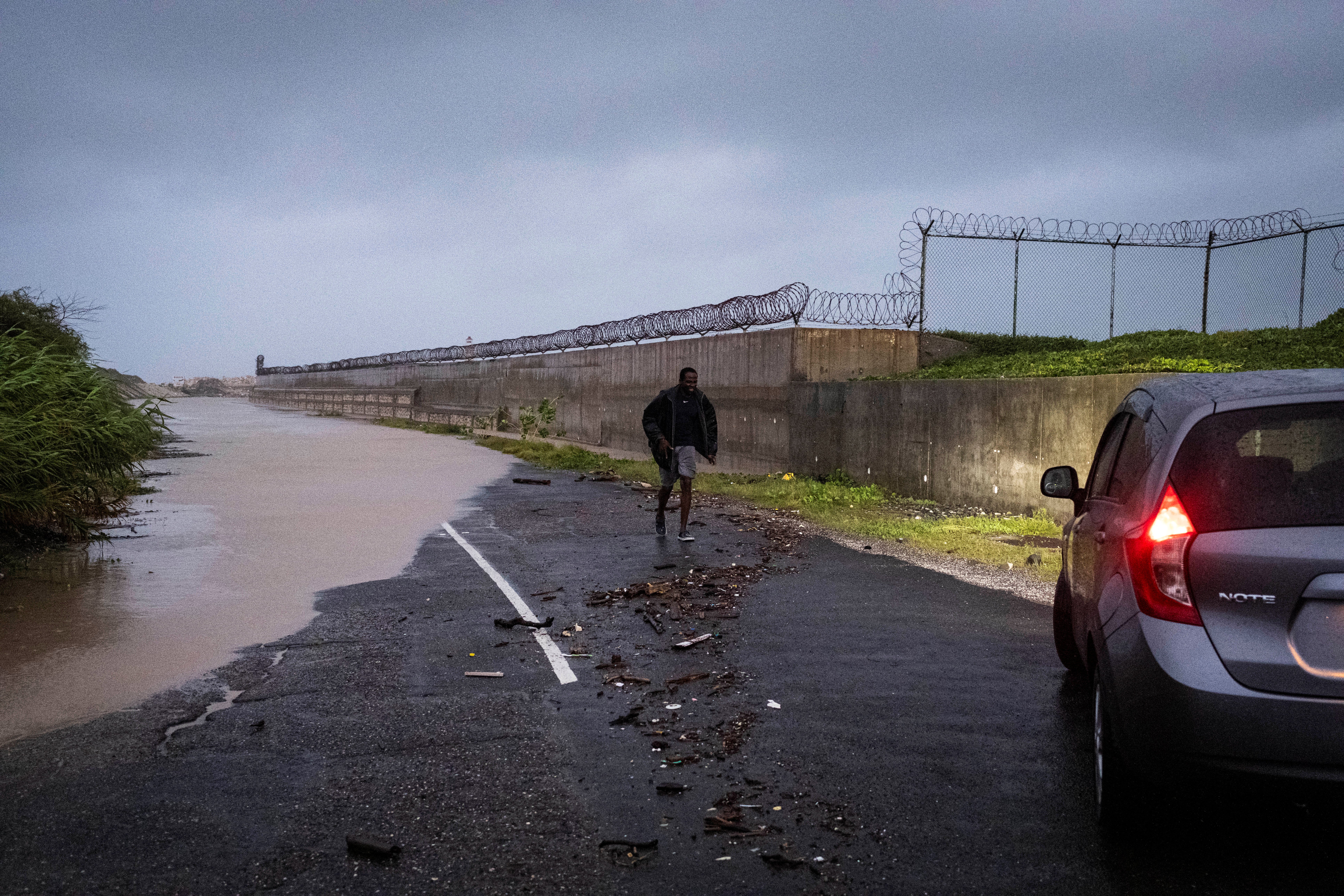 Um homem caminha até seu carro depois de avaliar uma estrada inundada quando o furacão Beryl atingiu a costa sul da ilha, em Kingston, Jamaica.