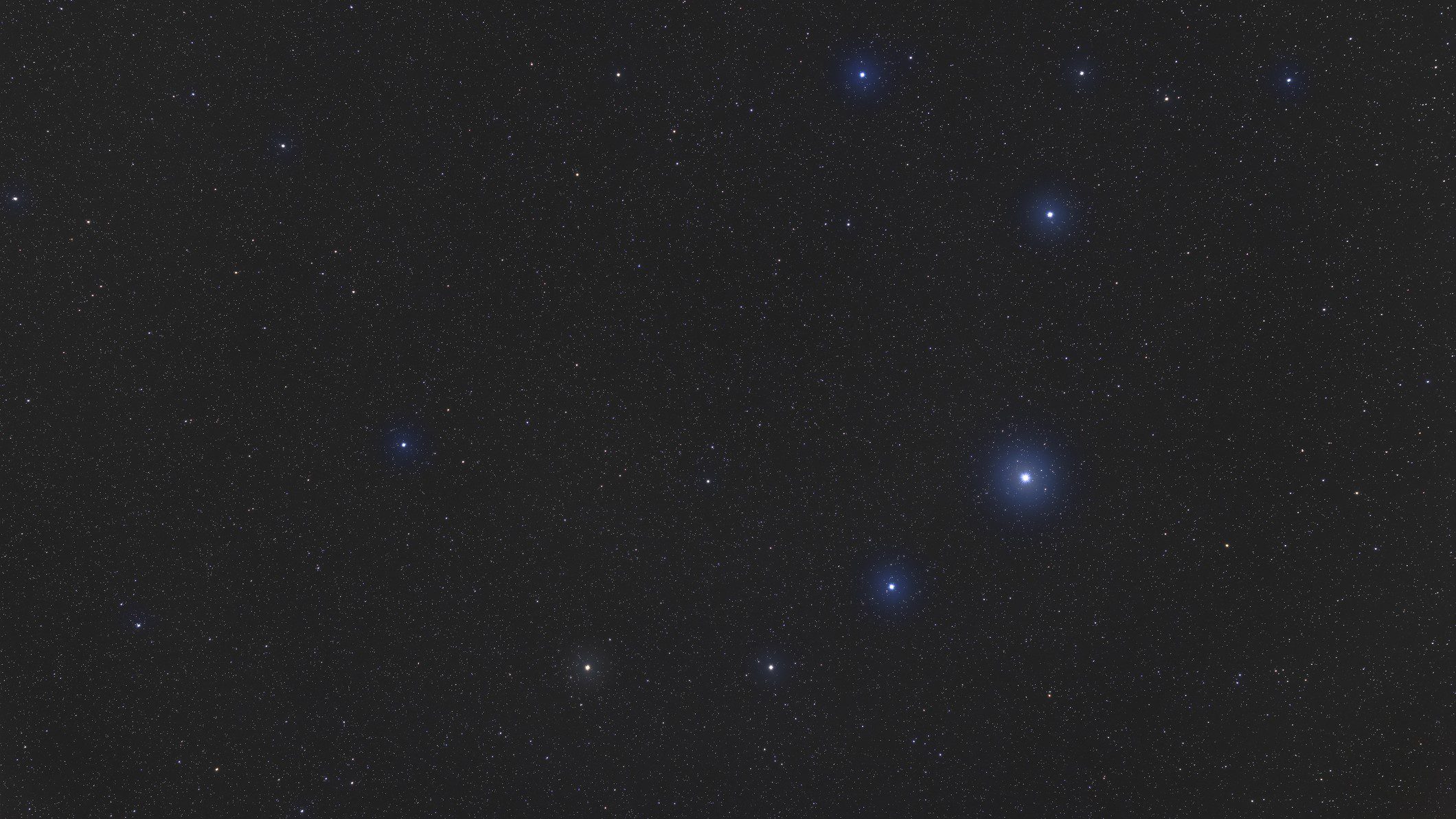 Uma série de pequenas estrelas azuis e brancas formam uma coroa em forma de arco no céu.