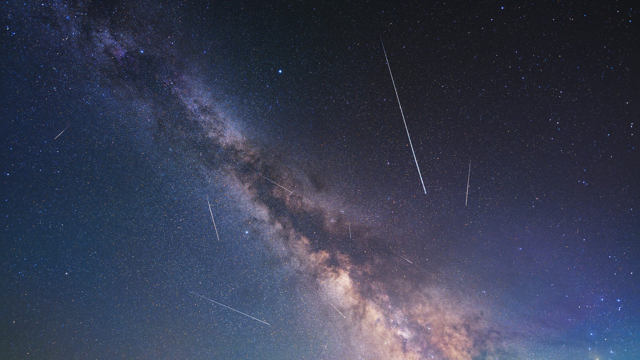 Trilhas de chuvas de meteoros aparecem como longas faixas brancas de luz contra o fundo da Via Láctea.