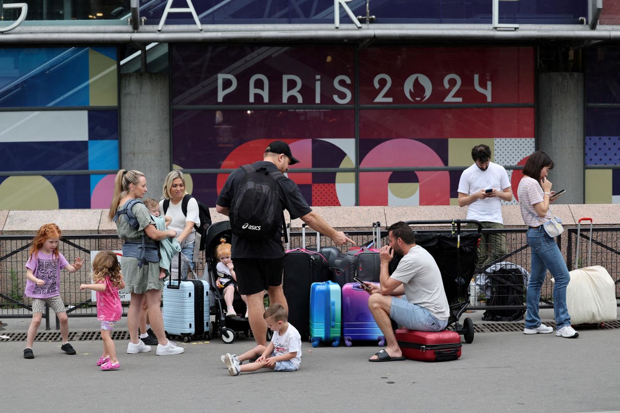 Viajantes de Sydney, na Austrália, esperam do lado de fora da estação ferroviária de Montparnasse, em Paris, enquanto tentam encontrar outros trens depois que sua viagem foi afetada por interrupções ferroviárias.