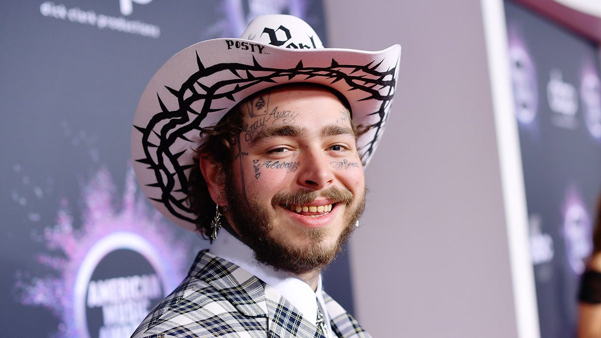 O rapper Post Malone usa um chapéu de cowboy rosa e terno combinando.