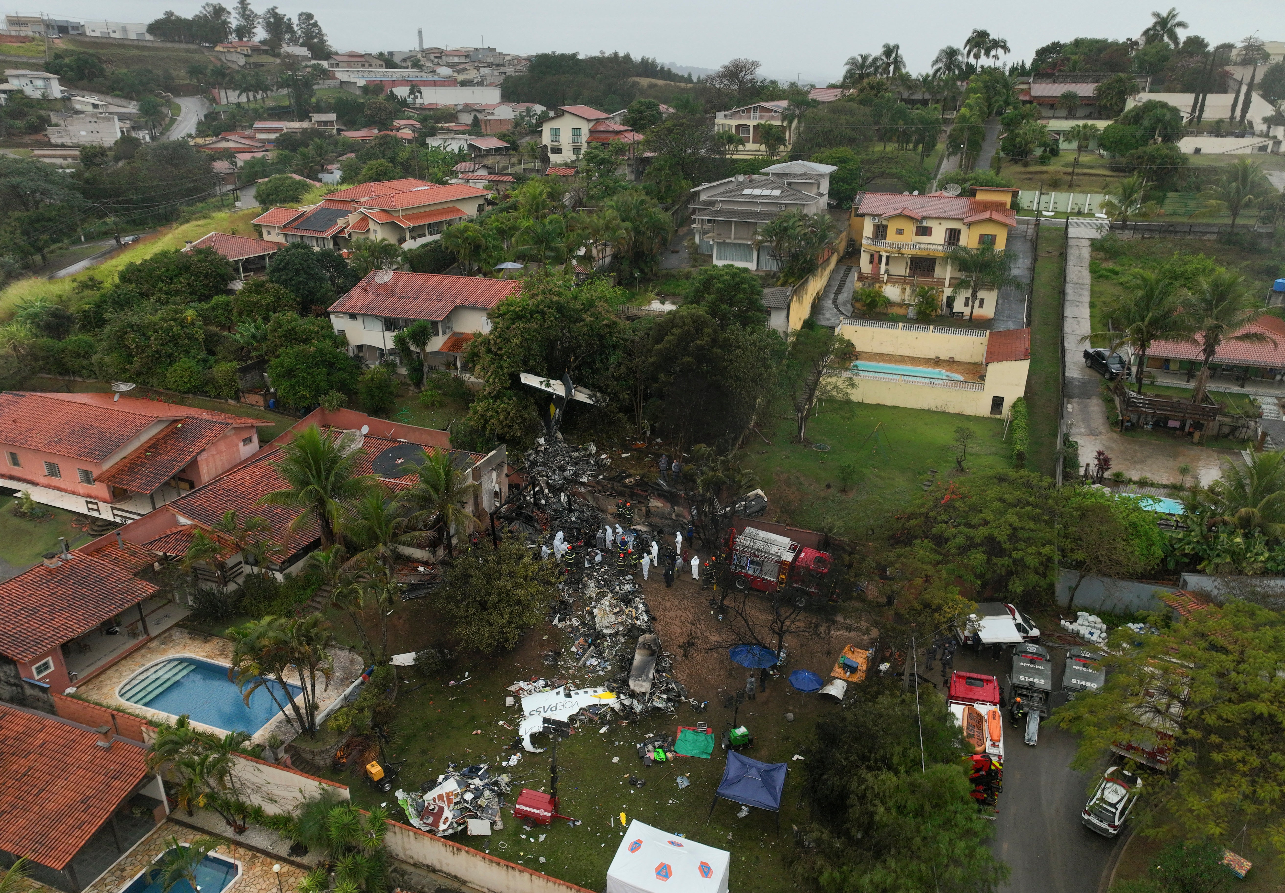 Bombeiros e equipes de resgate trabalham no local de queda de avião com 62 pessoas a bordo em área residencial de Vinhedo