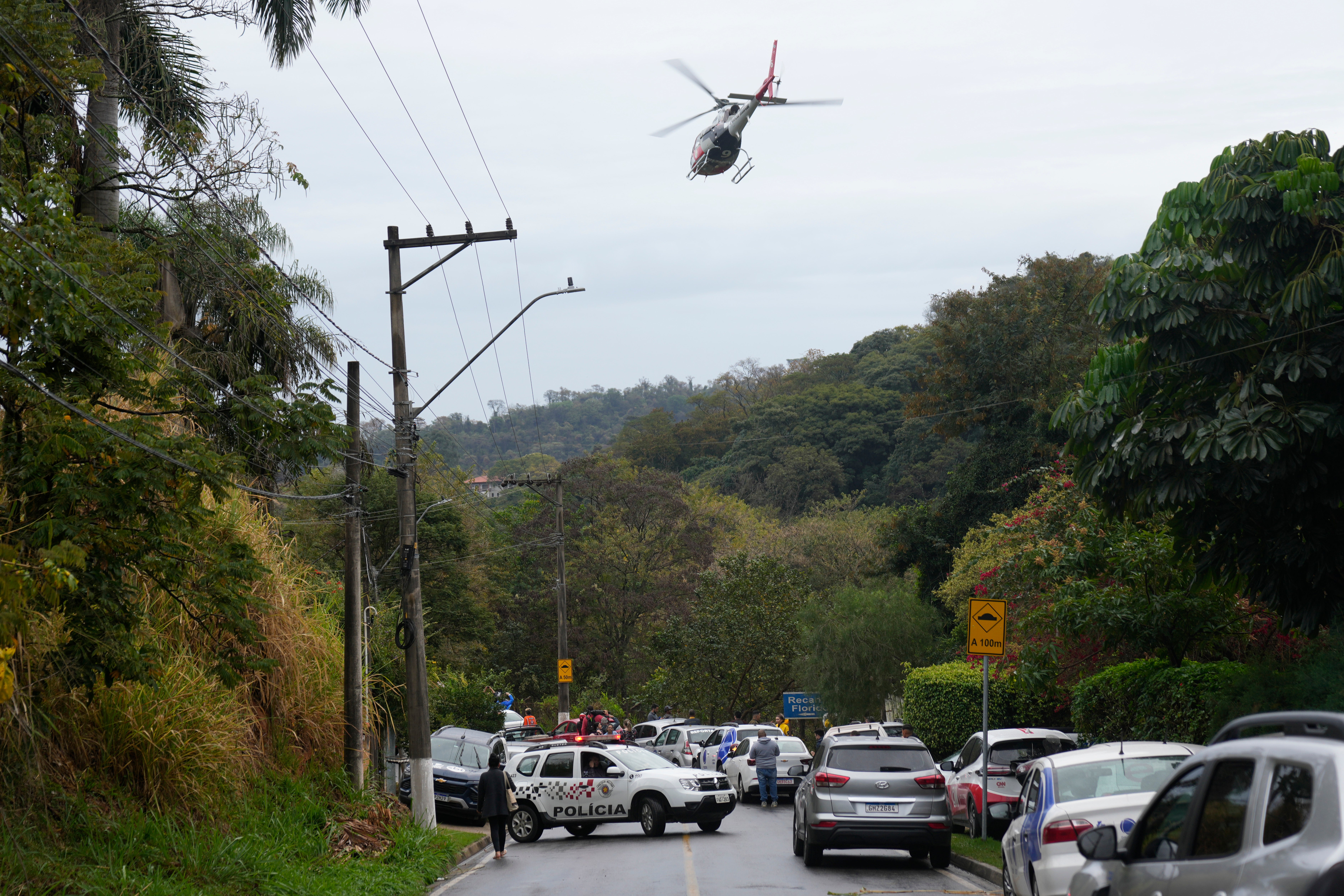 Um helicóptero sobrevoa o bairro onde o voo 2283 da Phoebus caiu na sexta-feira. Autoridades ainda não determinaram a causa do acidente